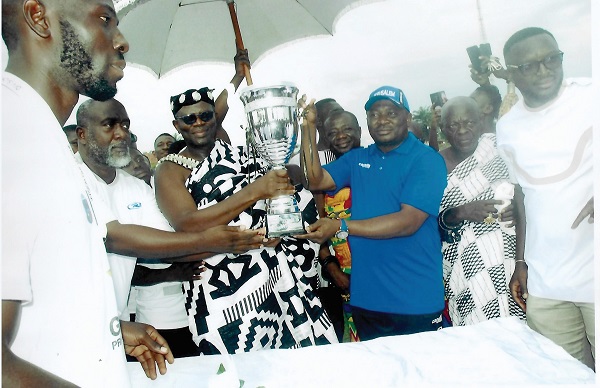 The Omanhene of the Akyem Kotoku Traditional Area, Oseadeeyo Dr Frimpong Manso IV (in cloth) being assisted by Mr Akwasi Acquah, Oda MP, and Mr Raymond Damptey (second left) to present the Division One Zone Three trophy to Kotoku Royals